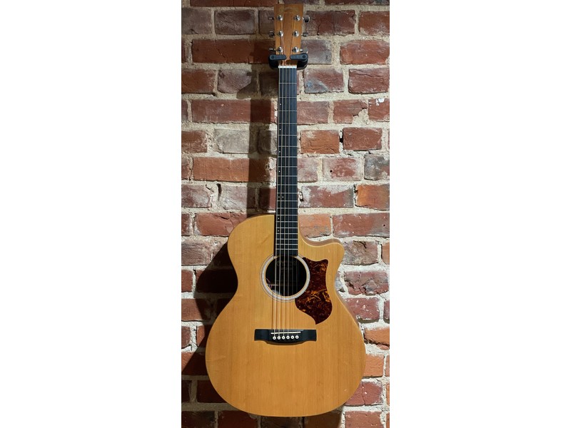 The Martin GPCPA5K is an acoustic-electric guitar from Martin’s Performing Artist series, designed to be a practical, stage-ready instrument rather than a traditional all-solid-wood Martin. It is in good used condition with a few playing marks and tarnishing on the hardware and includes a hard case. What it is A Grand Performance body acoustic-electric Single cutaway for upper fret access Built for live use, recording, and easy playability Body and construction Solid Sitka spruce top Koa-pattern high-pressure laminate (HPL) back and sides Scalloped X-bracing for balance and projection The solid top gives it real acoustic character, while the HPL body keeps cost down and improves durability. Tone and sound Balanced, clear tone with strong mids Designed to sit well in mixes rather than dominate acoustically  Plugged in, it performs particularly well thanks to its electronics, making it a “working musician’s guitar”. Electronics Fishman F1 Analog pickup system Built-in tuner, volume, and tone controls Designed for reliable, natural amplified sound This system makes it especially suitable for gigs and recording direct.  Neck and playability Performing Artist neck profile (slim and comfortable) 1.75" nut width Stratabond (laminated) neck for strength It’s known for being easy to play, especially over long sessions or live sets.  Design purpose The GPCPA5K was built to offer: Affordable entry into the Martin brand Strong plugged-in performance Comfortable, modern playability The Martin GPCPA5K combines a solid spruce top with durable laminate construction, a comfortable neck, and reliable electronics, making it a practical, gig-ready guitar.
